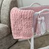 Chunky finger knit blanket in pink on a pink crochet moses basket